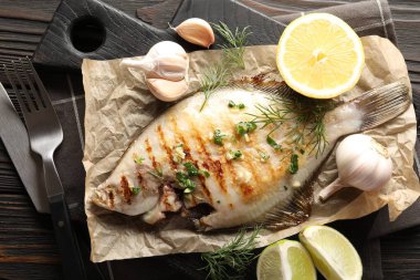 Ahşap masada servis edilen baharatlı, kavrulmuş pisi balığı. Ev yapımı deniz ürünleri yemeği.