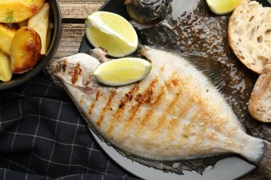 Tahta masada patates, ekmek ve limon dilimleri ile servis edilen kızarmış balık. Ev yapımı deniz ürünleri yemeği.