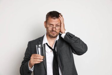 Beyaz arka planda bir bardak su içen adam akşamdan kalma.