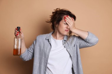 Bir şişe alkollü kadın bej arka planda akşamdan kalma.