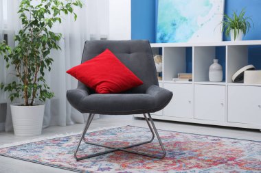 Oturma odasında kırmızı yastıklı rahat gri koltuk. İç tasarım