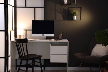 Ofiste bilgisayar, kırtasiye ve gözlüklü bir masa. İç tasarım