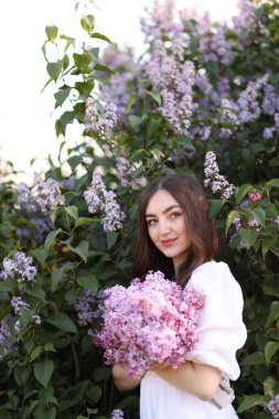 Leylak çiçeklerinin arasında güzel bir kadın ve açık havada bırakır