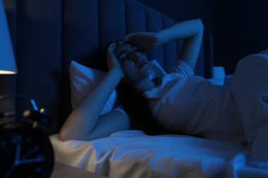 Evde yatakta uykusuzluk çeken hayal kırıklığına uğramış bir kadın.