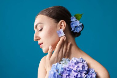 Mavi arka planda hortensiya çiçekleri olan güzel genç bir kadın.