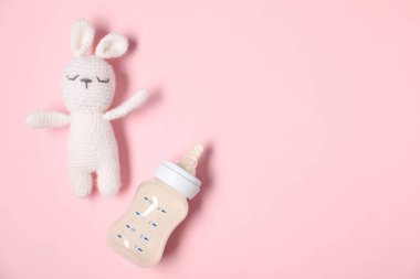 Besleme şişesi ve pembe arka planda oyuncak tavşan, düz yatıyordu. Metin için boşluk