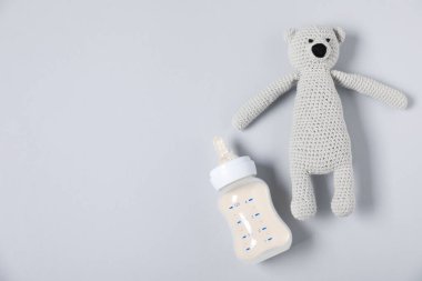 Gri arka planda mama şişesi ve oyuncak ayıyla besleniyor. Metin için boşluk