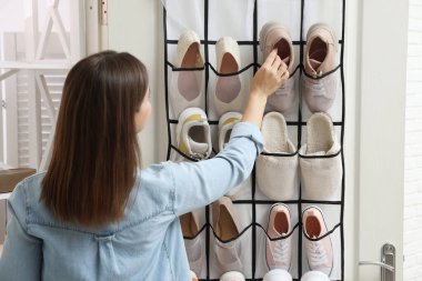 Bir kadın spor ayakkabısını evde, arka planda düzenleyiciye takıyor. Ayakkabı deposu