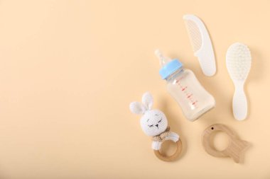 İçinde süt ve bej arka planda bebek aksesuarları olan bir şişe. Metin için boşluk