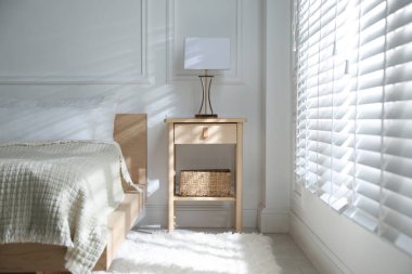 Yatağın yanında lamba olan komodin.