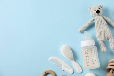 Açık mavi zemin üzerinde süt ve bebek aksesuarları olan bir şişe. Metin için boşluk
