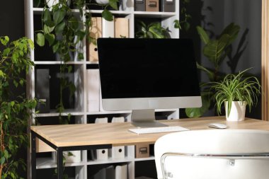 Ofisinde modern bilgisayar ve çiçek dekoru olan şık bir iş yeri. Biyofilik iç tasarım