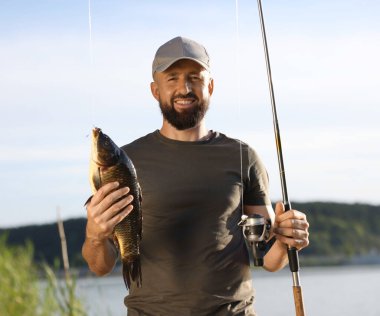 Gülümseyen balıkçılar oltayı tutar ve yazın göl kenarında balık yakalarlar.