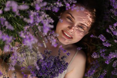Dışarıda lavanta çiçeklerinin arasında uzanan güzel genç bir kadın.