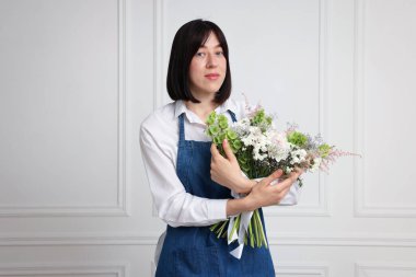 Beyaz duvarın yanında güzel çiçek buketi olan bir çiçekçi.