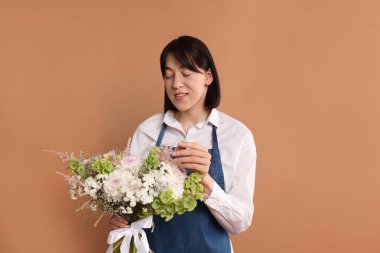 Koyu bej arka planda güzel çiçek buketi olan bir çiçekçi.