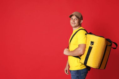 Kırmızı arka planda termo çantalı kurye, mesaj için boşluk. Yemek dağıtım servisi.