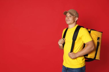 Kırmızı arka planda termo çantalı kurye, mesaj için boşluk. Yemek dağıtım servisi.