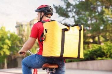 Termo çantalı kurye dışarıda bisiklet sürüyor. Yemek dağıtım servisi.