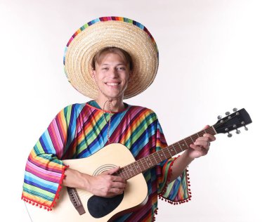 Sombrero şapkalı ve renkli pançolu gülümseyen adam beyaz arka planda gitar çalıyor.