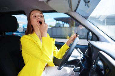 Hazırlanıyor. Genç bir kadın arabaya ruj sürüyor.