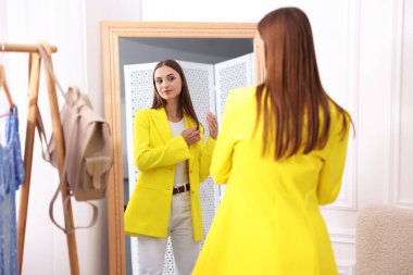 Hazırlanıyor. Evde aynanın yanında kıyafet deneyen genç bir kadın.