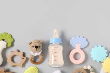 Açık gri zemin üzerinde süt ve bebek aksesuarları olan bir şişe. Metin için boşluk
