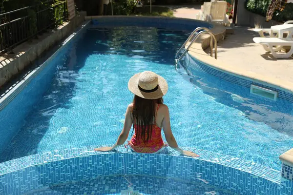 Yüzme havuzunda hasır şapkalı bir kız.
