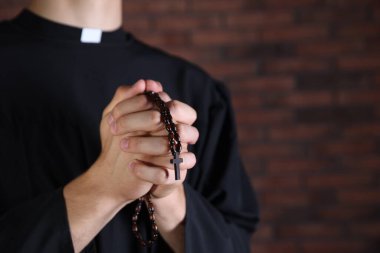 Tuğla duvarın yanında dua eden rahip, yaklaş. Metin için boşluk