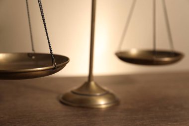 Tahta masanın üzerindeki adalet terazileri bej arka planda, yakın plan