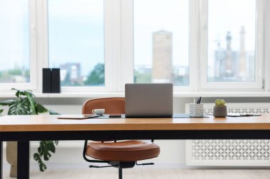 Modern dizüstü bilgisayarı ve ahşap masa üzerindeki kırtasiyesi olan şık bir iş yeri.