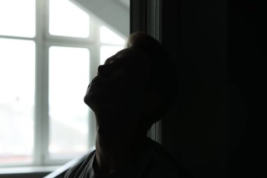 Üzüntü ve depresyon. Karanlık odada yorgun bir adam. Penceresi açık, gün ışığı var.