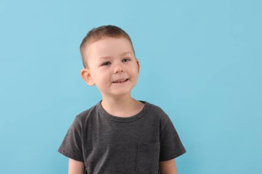 Açık mavi arka planda gülümseyen çocuk portresi
