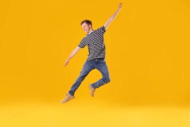 Turuncu arka planda zıplayan mutlu genç adam