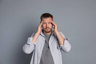 Gri arka planda akşamdan kalma bir adam.