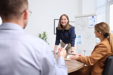 İş koçu ofisteki bir grup insana sunum yapıyor.