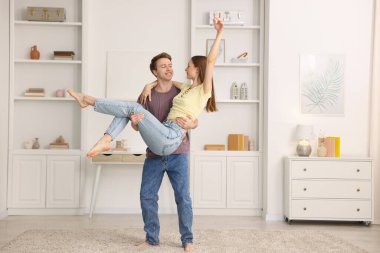 Mutlu genç çift evde dans ediyor.