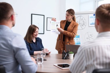 İş koçu ofisteki bir grup insana sunum yapıyor.