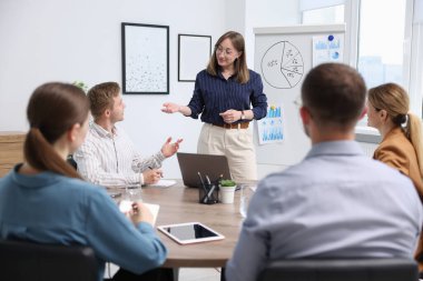 İş koçu ofisteki bir grup insana sunum yapıyor.