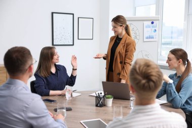 İş koçu ofisteki bir grup insana sunum yapıyor.