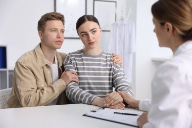 Tüp bebek (tüp bebek). Üreme kliniğine yaptığı ziyarette üzgün çifti destekleyen doktor