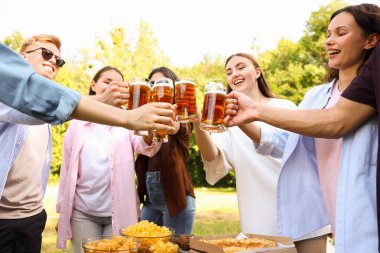 Bir grup mutlu arkadaş dışarıda bira bardaklarını tokuşturuyor.