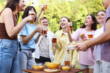 Bir grup mutlu arkadaş dışarıda bira içip eğleniyorlar.