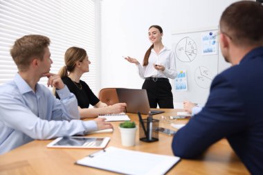 İş koçu ofisteki bir grup insana sunum yapıyor.