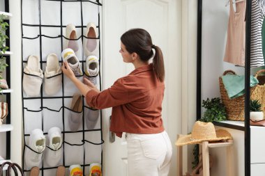 Evde spor ayakkabısını düzenleyiciye takan bir kadın. Ayakkabı deposu