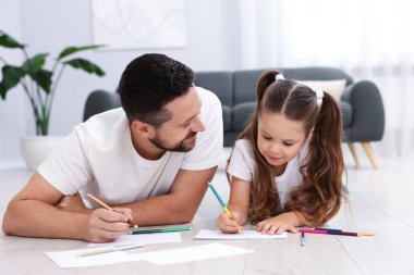 Baba ve kızı evdeki sıcak zeminde birlikte resim çiziyorlar. Isıtma sistemi