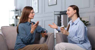 Ofisteki koltuklarda kahve molası sırasında iş arkadaşları konuşuyor.