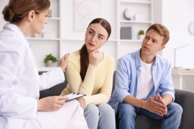 Tüp bebek (tüp bebek). Üreme kliniğine yaptığı ziyarette üzgün çifti destekleyen doktor