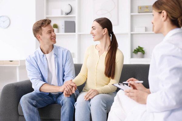 Оплодотворение in vitro (ЭКО). Пара держащихся за руки во время приема у врача в репродуктивной клинике