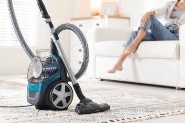 Evdeki kanepede dinlenen kadın, elektrik süpürgesine odaklan.